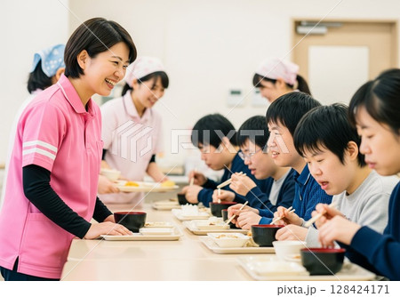 障がい者施設で食事を配膳する笑顔の女性介護士 配膳、ランチタイム、給食、食事、楽しみ 128424171