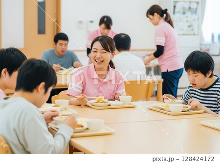 障がい者施設で食事を配膳する笑顔の女性介護士 配膳、ランチタイム、給食、食事、楽しみ 128424172