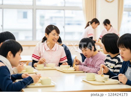 障がい者施設で食事を配膳する笑顔の女性介護士 配膳、ランチタイム、給食、食事、楽しみ 128424173