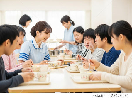 障がい者施設で食事を配膳する笑顔の女性介護士 配膳、ランチタイム、給食、食事、楽しみ 128424174