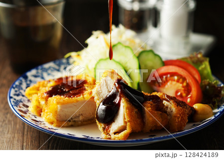 チキンカツに特製ソースをかける 128424189