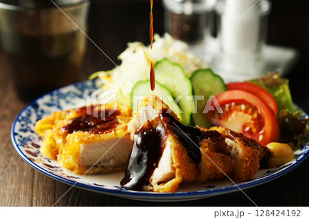 チキンカツに特製ソースをかける 128424192