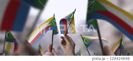 Comoros flags in their hands on a blurred urban background 128424698