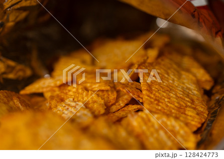 Overhead perspective inside a vibrant, crinkled bag reveals delicious, textured potato chips, emphasizing crunchy, savory flavor, ideal for indulgent, casual snacking moments 128424773
