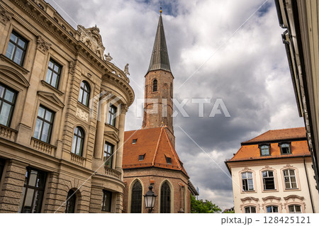 Historic St. Jakobs Church in Munich Near Sendlinger Tor: Elegant Gothic Architecture with Tall Steeple and Red Roof Surrounded by Classic Bavarian Buildings under Dramatic Cloudy Sky Historic St. Jakobs Church in Munich Near Sendlinger Tor: Elegant Gothic Architecture with Tall Steeple and Red Roof Surrounded by Classic Bavarian Buildings under Dramatic Cloudy Sky 128425121