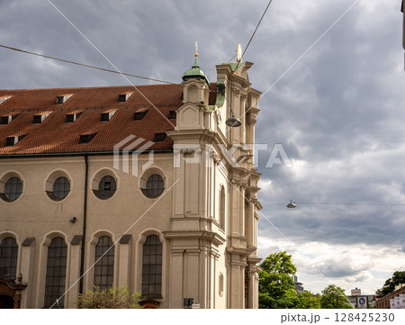 Historic Church Of The Holy Spirit In Munich: Elegant Baroque Architecture With Tower And Facade Near Marienplatz Under Dramatic Cloudy Sky 128425230