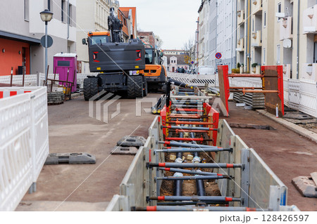 New modern insulated urban pipeline installation construction site  exposed underground pipes in shored trenches. Insulated steel pipes lie connection engineering infrastructure upgrade work 128426597