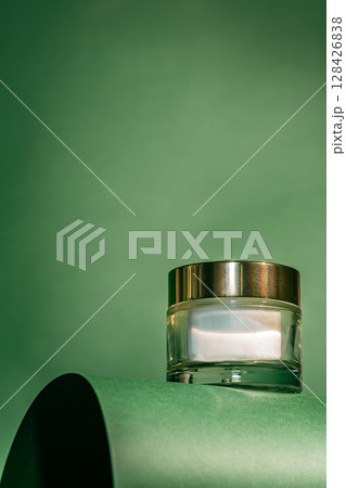 A glass jar of rich-textured face cream on green A glass jar of rich-textured face cream on green 128426838