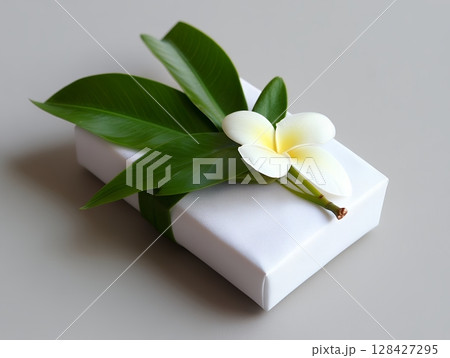 Elegant White Gift Box Decorated with Green Leaves and Plumeria Flower spa zen pure calm fresh clean 128427295