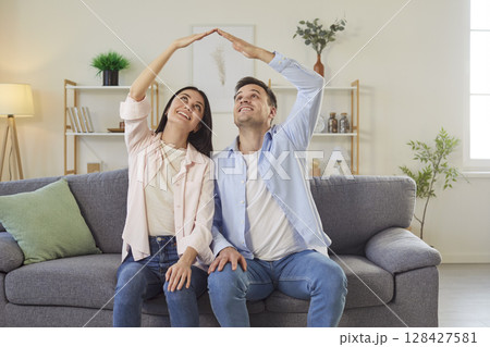 Family Couple Showing Roof Sign On Sofa At Home 128427581