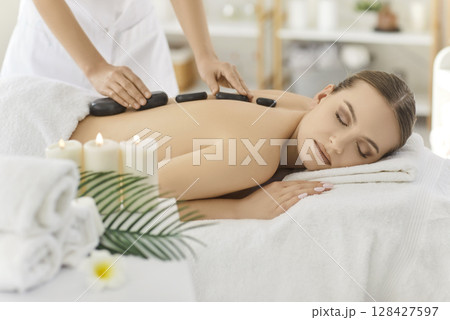 Masseuse Performing Stone Massage In Spa Salon 128427597