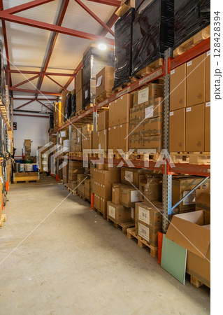 Cardboard boxes sitting on wooden pallets filling warehouse storage space 128428394