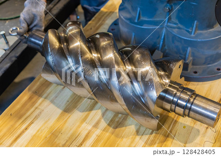 Worker holding screw compressor rotor during maintenance operations 128428405