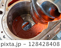 Large screw conveyor inside industrial gearbox showing red paint and metal housing 128428408