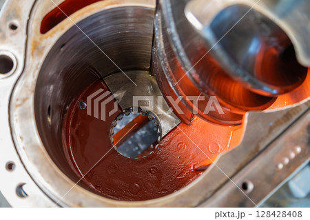 Large screw conveyor inside industrial gearbox showing red paint and metal housing 128428408