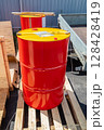 Red and yellow metal barrels resting on wooden pallet 128428419
