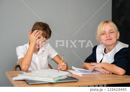 Boy Girl Homework - Boy doing homework at a table while girl looks on. Boy Girl Homework - Boy doing homework at a table while girl looks on. 128428495