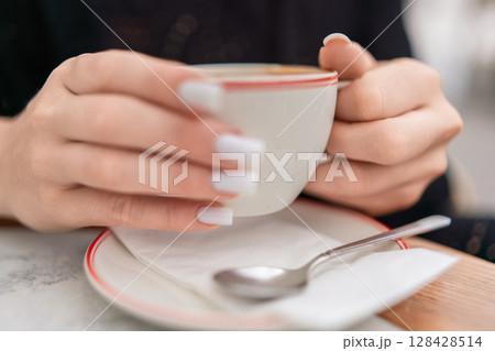 Coffee Cup Hands: Woman enjoys caffeine break indoors, holding hot drink for warmth comfort, daytime. 128428514