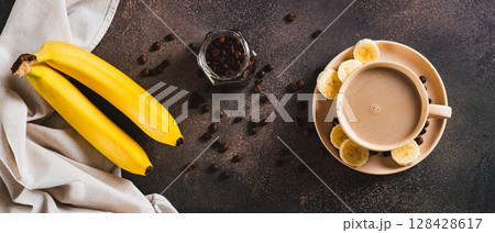 Blended frozen banana coffee in a cup on the table top view web banner 128428617