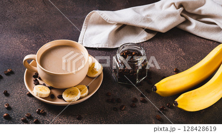 Alternative cold banana coffee in a cup on the table web banner 128428619