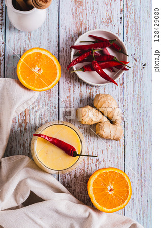 Orange ginger smoothie with pepper for weight loss in a glass top and vertical view Orange ginger smoothie with pepper for weight loss in a glass top and vertical view 128429080