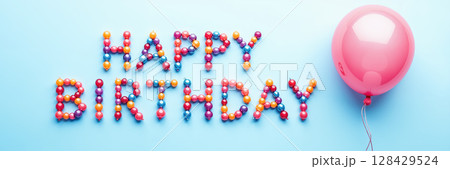 Colorful beads spell Happy Birthday with a pink balloon. 128429524