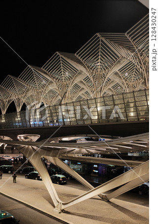 Modern illuminated architecture of Oriente Station at night in Lisbon Portugal featuring geometric roof design arches and empty railway tracks in futuristic urban environment. High quality photo Modern illuminated architecture of Oriente Station at night in Lisbon Portugal featuring geometric roof design arches and empty railway tracks in futuristic urban environment. High quality photo 128430247