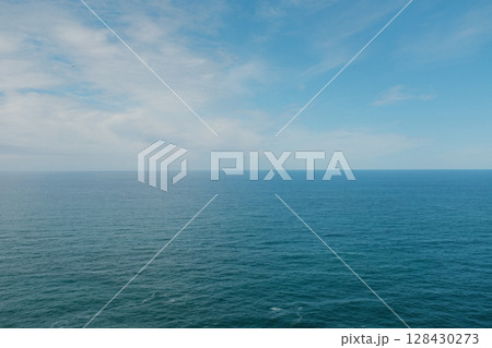 Scenic view of Cabo da Roca steep rocky cliffs meeting blue Atlantic Ocean under bright sky in Sintra Portugal panoramic coastal landscape from westernmost point of mainland Europe 128430273