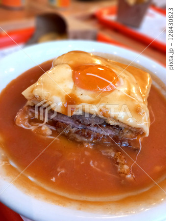 Traditional Portuguese Francesinha Sandwich with Melted Cheese and Fried Egg in Rich Beer Sauce 128430823