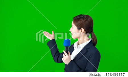 マイクを持って説明する女性レポーター 128434117