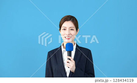 マイクを持って話す女性アナウンサー マイクを持って話す女性アナウンサー 128434119