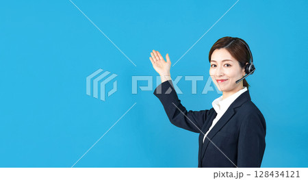 ヘッドセットをつけて説明する女性スタッフ ヘッドセットをつけて説明する女性スタッフ 128434121
