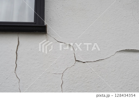 劣化してひび割れした白い外壁と窓枠 劣化してひび割れした白い外壁と窓枠 128434354