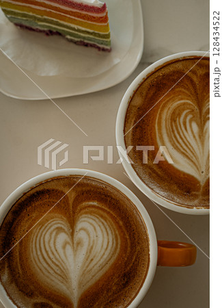 Cups of coffee decorated with a heart and rainbow cake Cups of coffee decorated with a heart and rainbow cake 128434522