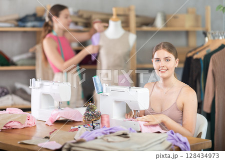 Adult woman sews female assistant working with mannequin 128434973