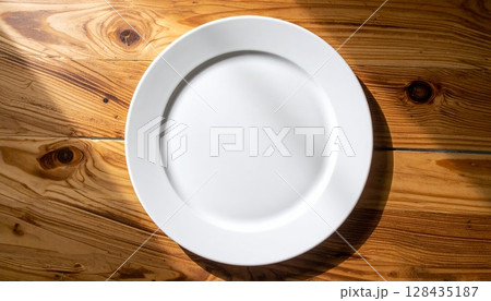 温かい木目と白いプレート:自然光が当たる食卓の準備 温かい木目と白いプレート:自然光が当たる食卓の準備 128435187
