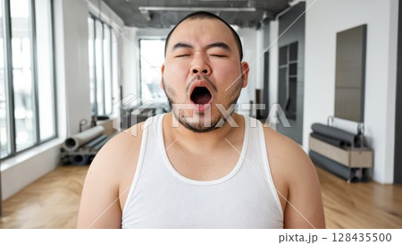 スタジオで大きくあくびをする坊主頭の日本人男性 128435500
