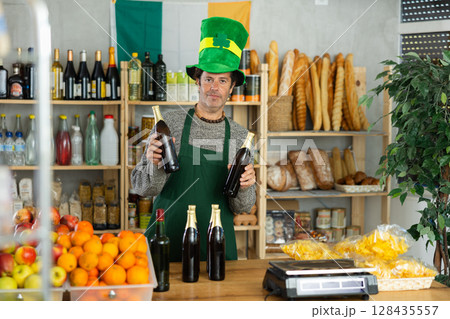 Salesman in green leprechaun hat offering beer on St. Patricks Day 128435557