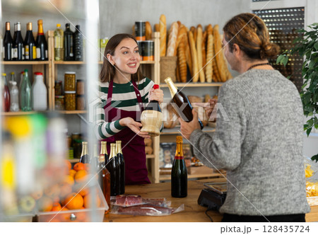 Saleswoman offering options of alcoholic drinks to customer in store Saleswoman offering options of alcoholic drinks to customer in store 128435724