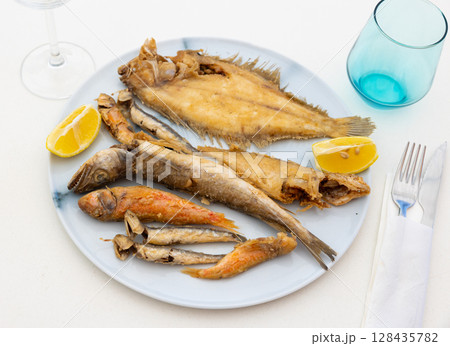 On white background, there is plate with fried fish of different varieties 128435782