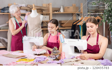 Woman and girl tailors sewing, senior female designer work with mannequin. 128435783