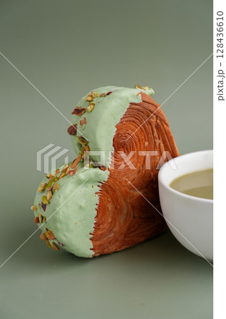 Green tea Matcha latte cappuccino beverage Morning breakfast gift idea Heart shaped pistachio croissant on green background with copy space. Puff pastry trendy sweet dessert bakery. Creamy dough 128436610