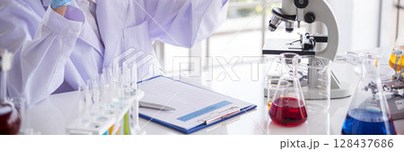 Banner Asian woman scientist hand write note research in medical lab look at science microscope. Panorama biology chemistry lab. Asian Female technician laboratory using microscope with copy space 128437686