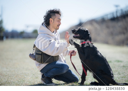 青空の河川敷で散歩を楽しむ男性と犬 見つめ合うハイタッチやお手 信頼、親友やバディのイメージ 青空の河川敷で散歩を楽しむ男性と犬 見つめ合うハイタッチやお手 信頼、親友やバディのイメージ 128438830