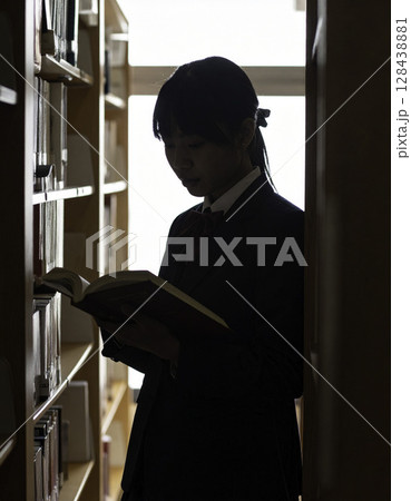 図書館で静かに本を読む女子高校生、逆光シルエットが描く学びと知的探求の時間 128438881