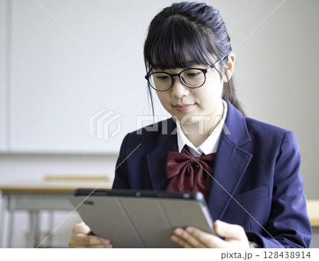 教室でタブレット学習をする眼鏡の日本人女子高校生（制服・集中・学び） 128438914