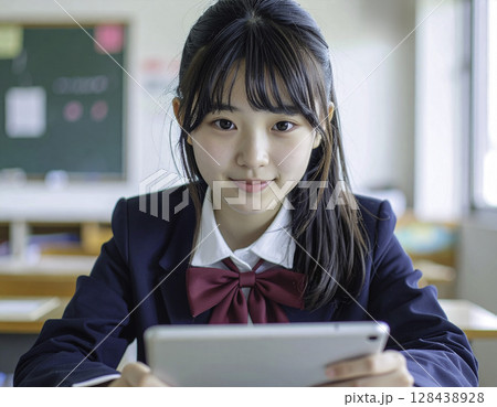 笑顔でタブレットを持つ日本人女子高校生（教室・制服・ICT教育・未来・学び） 128438928