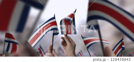Costa Rica flags in their hands on a blurred urban background 128439843