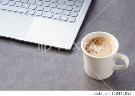 淹れたての美味しいコーヒーを飲みながら、ノートパソコンでデスクワークをしているイメージ 128441858