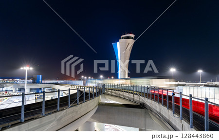 Night view of motion-blurred train and illuminated Air Traffic Control tower at San Francisco International Airport, California, United States 128443860
